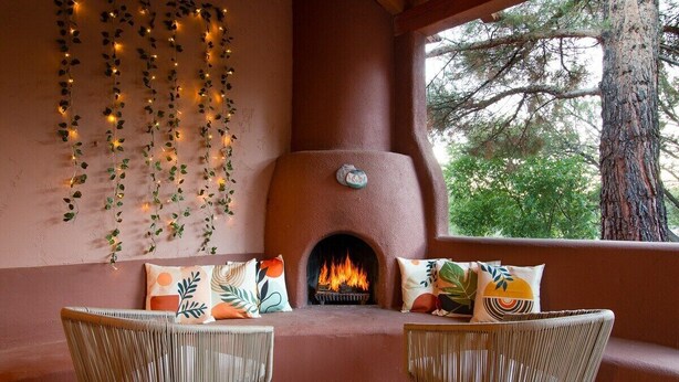 A cozy seating area with a fireplace, wicker chairs, and decorative plants. - Enchanted Adobe Hideaway w/Hot Tub & GIANT Chess (Sedona)
