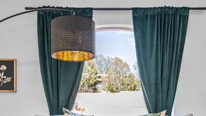 Ein modernes Wohnzimmer mit einem schwarzen Ledersofa, zwei runden Couchtischen und grünen Sesseln.