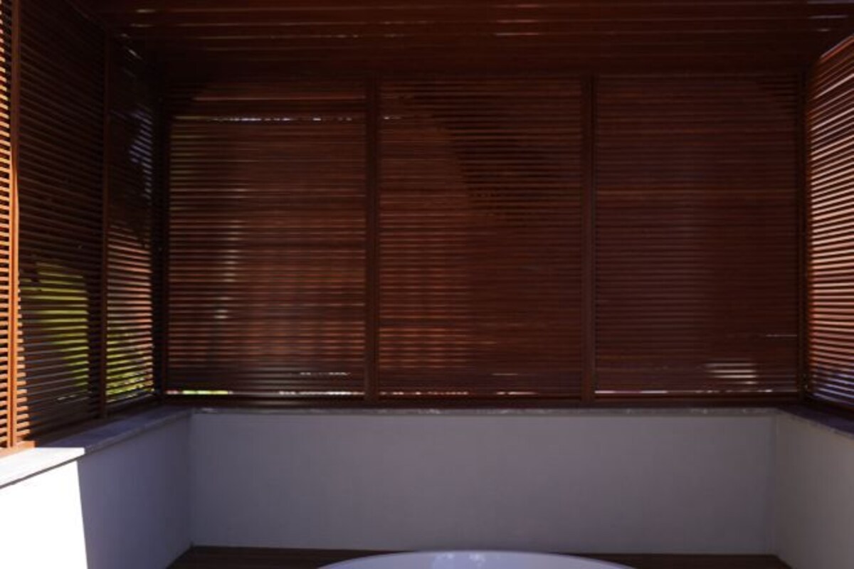 A room with a wooden slatted ceiling, a white bathtub, and a white wall.