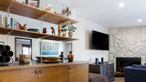 A modern living room with a wooden cabinet, a stone fireplace, and a flat-screen TV mounted on the wall. - Perfectly Located 2 Minute Walk Lift Downtown Avon (Avon)