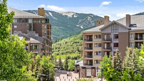 A multi-story hotel with balconies, surrounded by lush greenery and mountains in the background. - Perfectly Located 2 Minute Walk Lift Downtown Avon (Avon)