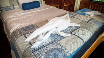 Una cama con una colcha estampada y una toalla enrollada encima.