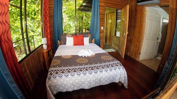 A bed with a patterned bedspread, a bedside lamp, and a window with curtains.