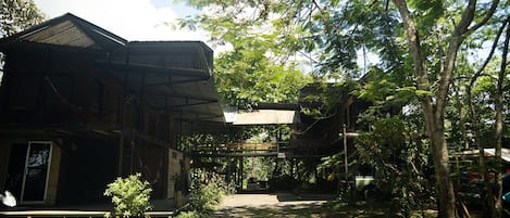 A traditional wooden house with a covered porch and a dirt pathway leading to it.