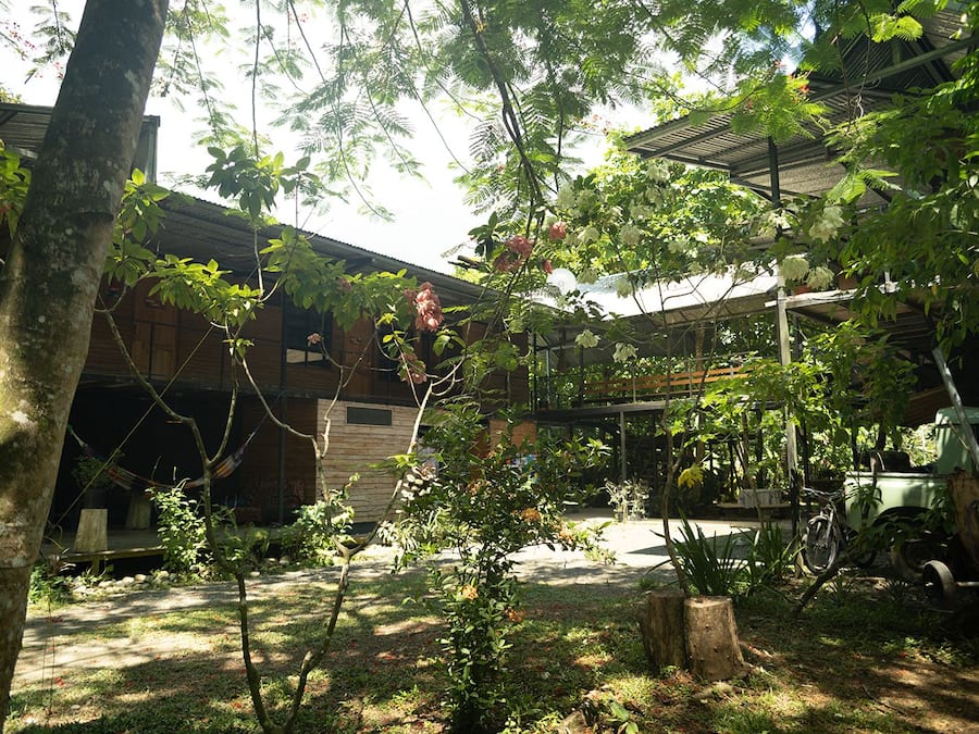 A courtyard with a wooden building, a hammock, and a bicycle.