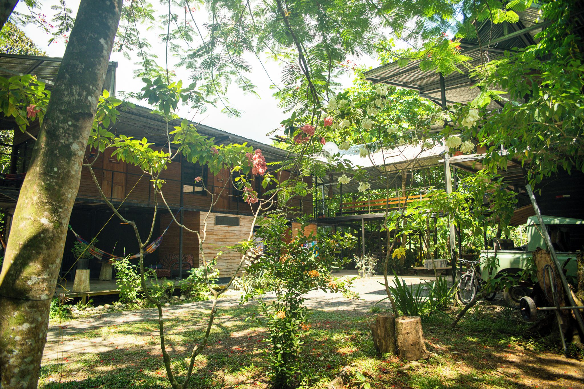 A courtyard with a wooden building, a hammock, and a bicycle.