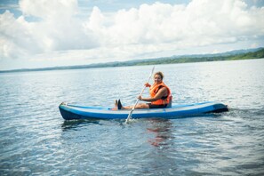 A person in a blue kayak on calm water with a distant shoreline. - Terrazas del Golfo  (Puerto Jiménez)