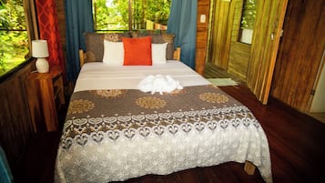 Una cama con una colcha estampada, almohadas y una toalla blanca.