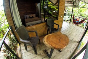 A wooden deck with a round table and two chairs, a hammock, and a view of the surrounding greenery. - Terrazas del Golfo  (Puerto Jiménez)