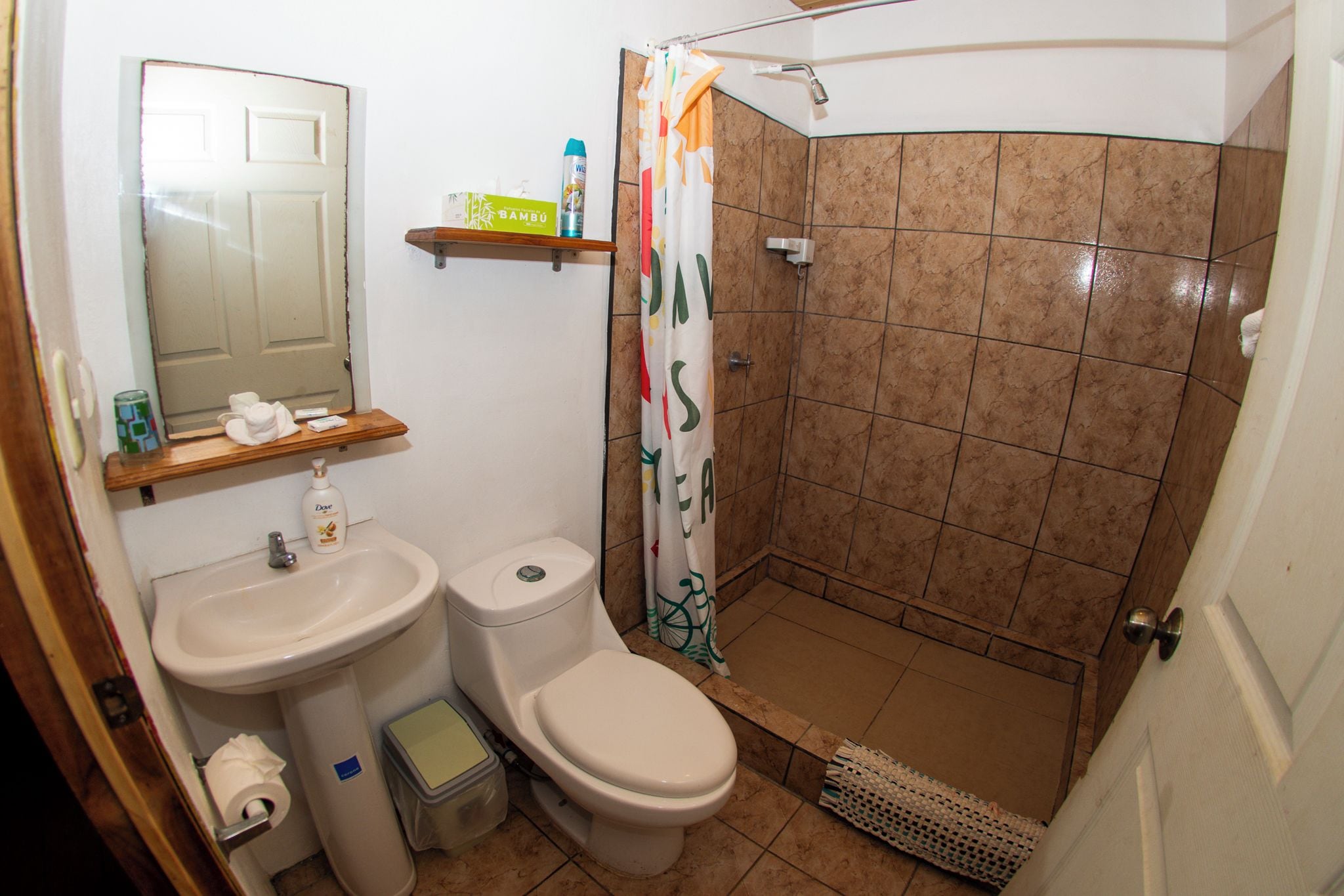 Un baño con inodoro, lavamanos, ducha y espejo.