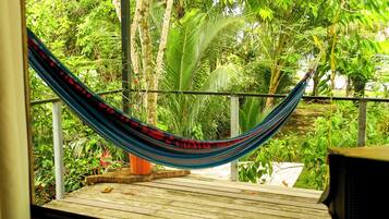A hammock on a wooden deck with a view of lush greenery.