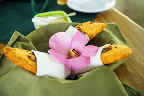 A green cloth with a pink flower and two triangular food items. - Terrazas del Golfo  (Puerto Jiménez)