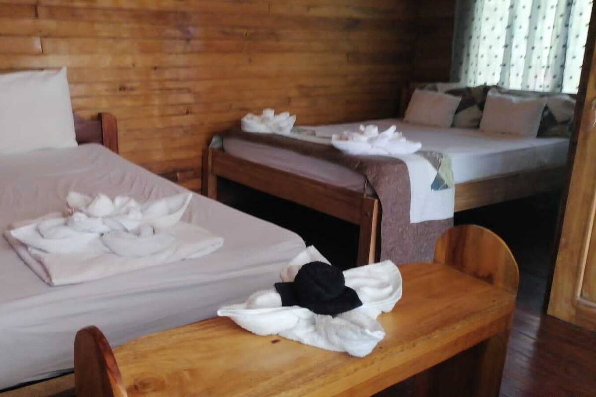 A room with two beds, wooden furniture, and neatly folded towels on the beds.