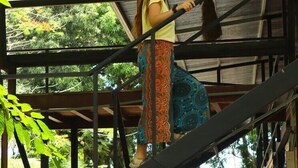 A person on a staircase with a metal railing, surrounded by greenery and a covered area with a roof. - Terrazas del Golfo (Puerto Jiménez)