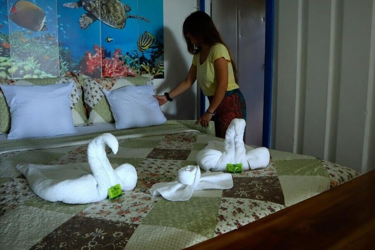 A bed with swan-shaped towels and a painting of marine life on the headboard.