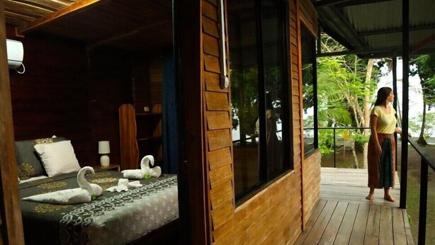 A wooden cabin with a bed, a window, and a balcony. - Terrazas del Golfo (Puerto Jiménez)