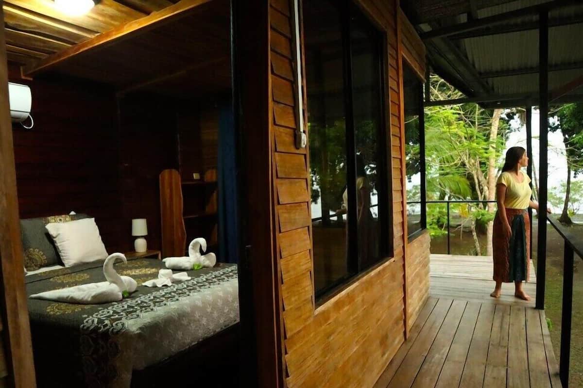 A wooden cabin with a bed, a window, and a balcony.