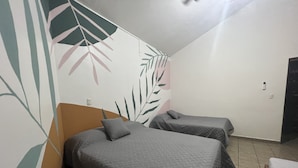 A room with two single beds, a wooden headboard, and a wall with a leaf pattern. - Apartamento Centro de Jaco, 100 Metros Playa, Comercios (Jacó)