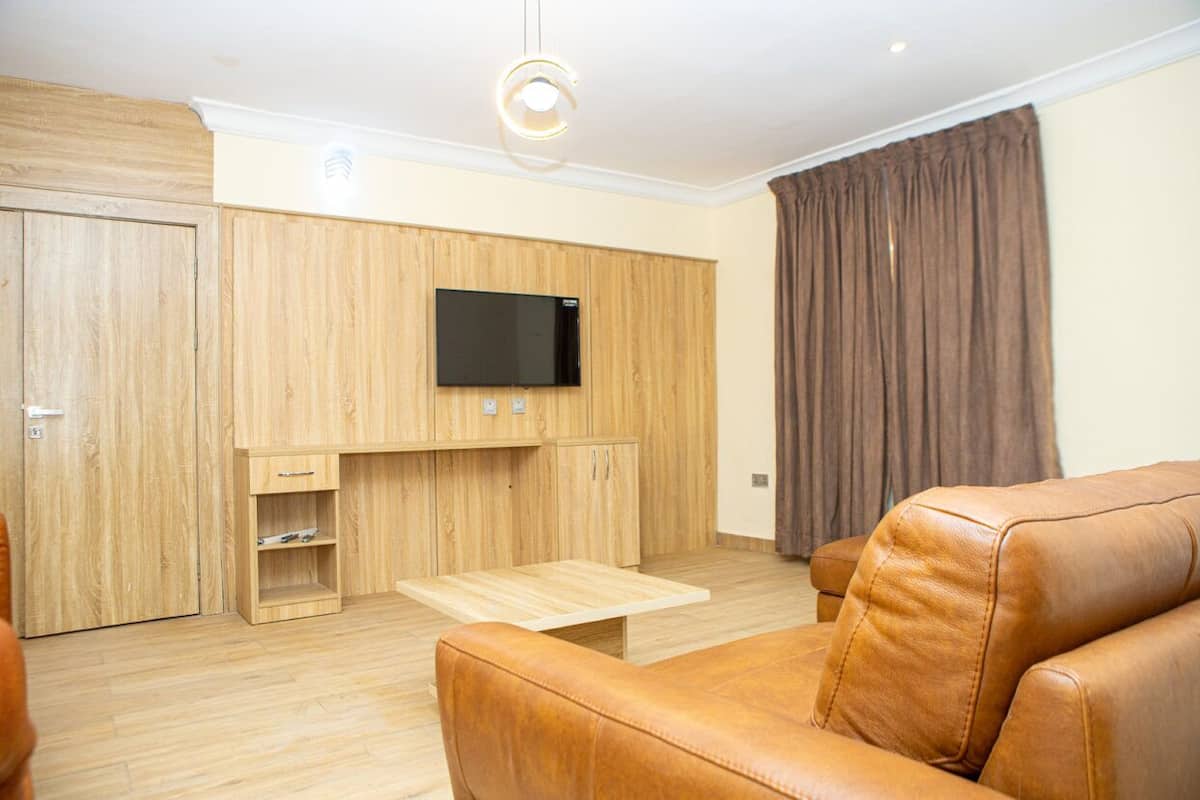Una sala moderna con un mueble de madera, un televisor de pantalla plana, un sofá de cuero y una mesa de centro de madera.