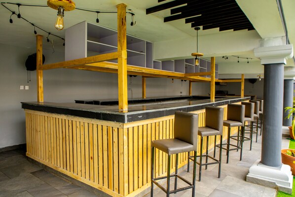 Un espace bar avec des tabourets en bois et un comptoir noir.
