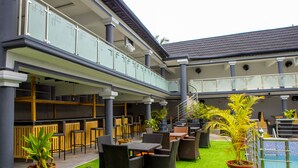 A multi-level outdoor seating area with wicker furniture and a pool. - Wingate Exotic (Ilorin)