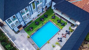 A multi-story hotel with a rooftop pool area, outdoor seating, and a well-maintained lawn. - Wingate Exotic (Ilorin)