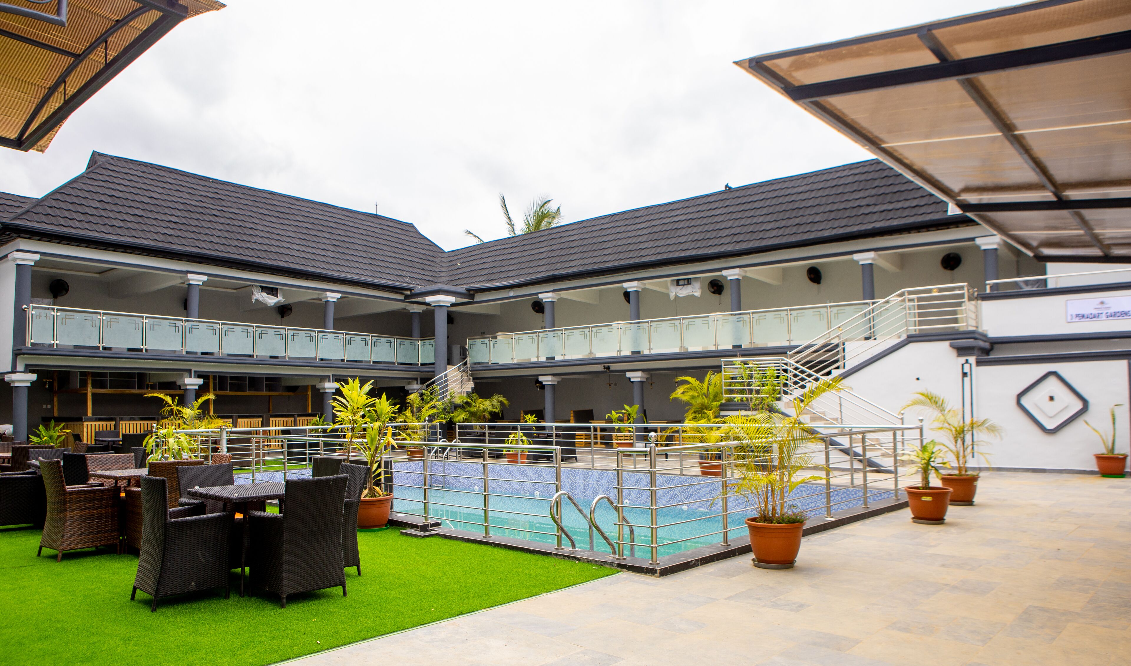 A two-story building with a covered outdoor pool area, outdoor seating, and potted plants.