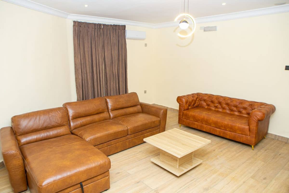 Una sala de estar con un sofá modular, un sofá capitonado y una mesa de centro de madera.