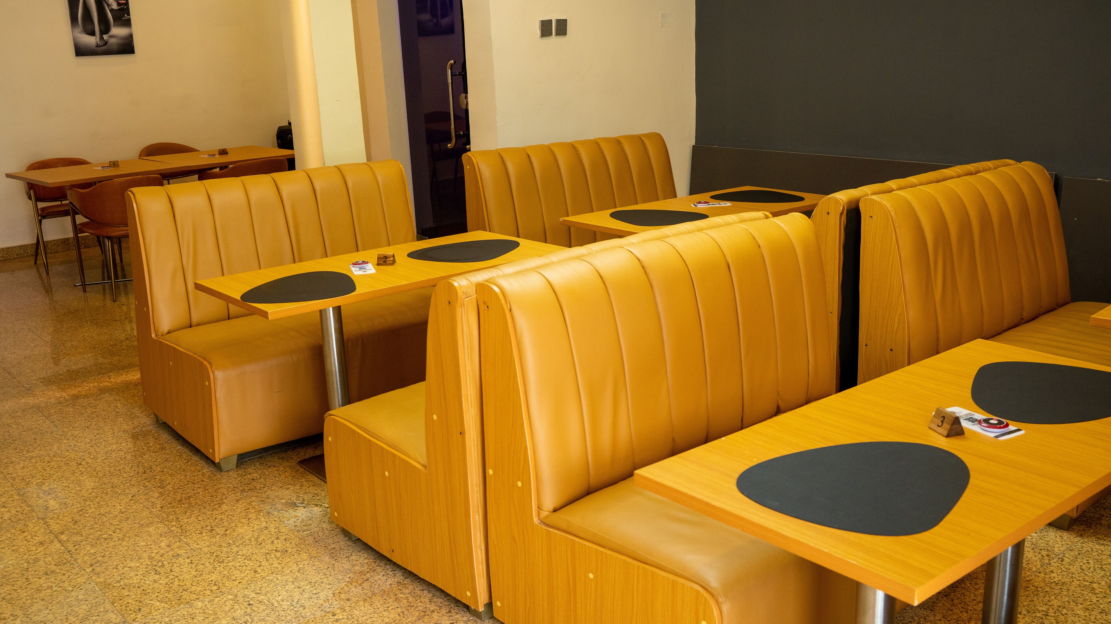 A seating area with booths and tables, some with black circular mats.