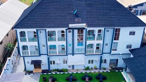 A multi-story building with a flat roof, large windows, and a sign reading "PEMADART GARDENS". - Wingate Exotic (Ilorin)