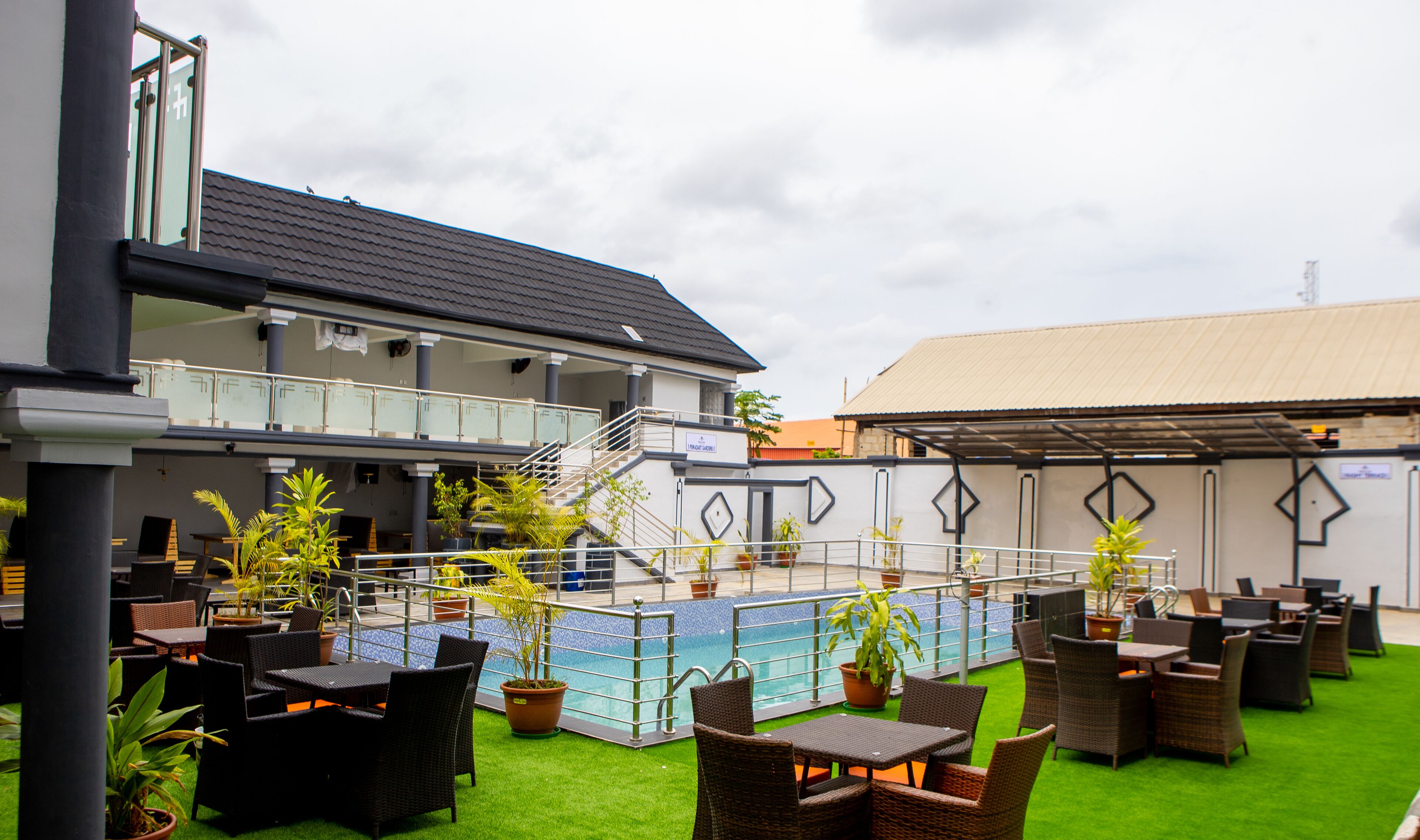 A hotel with outdoor seating, a pool, and a covered area.