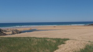 Ein Strand mit blauem Himmel, sandigem Ufer und einigen Felsen.