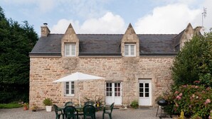 Ein Steinhaus mit Kieshof, Außenbestuhlung und Grillplatz.