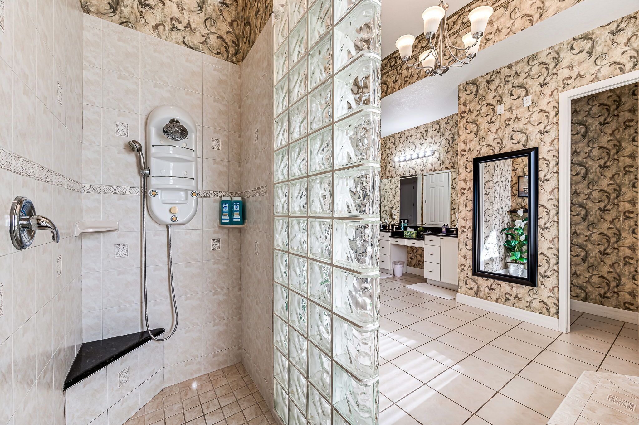 A modern bathroom with a glass shower enclosure, a built-in vanity, and a large mirror.