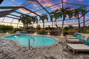 A pool area with a covered structure, lounge chairs, and palm trees. - Gulf Access, Pool, Spa, Dock: Lighthouse (Cape Coral)