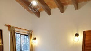 A bedroom with a wooden bed, a window with curtains, two wall-mounted lights, and a wooden door. - Villas Tequisquiapan  (Tequisquiapan)