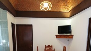 A room with a wooden dining table and chairs, a television on a shelf, and a patterned rug on the floor. - Villas Tequisquiapan  (Tequisquiapan)