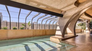 Área de piscina interior moderna com teto de vidro e arquitetura em concreto.