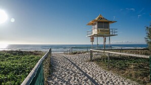 Uma torre salva-vidas numa praia arenosa com vista ampla para o oceano.