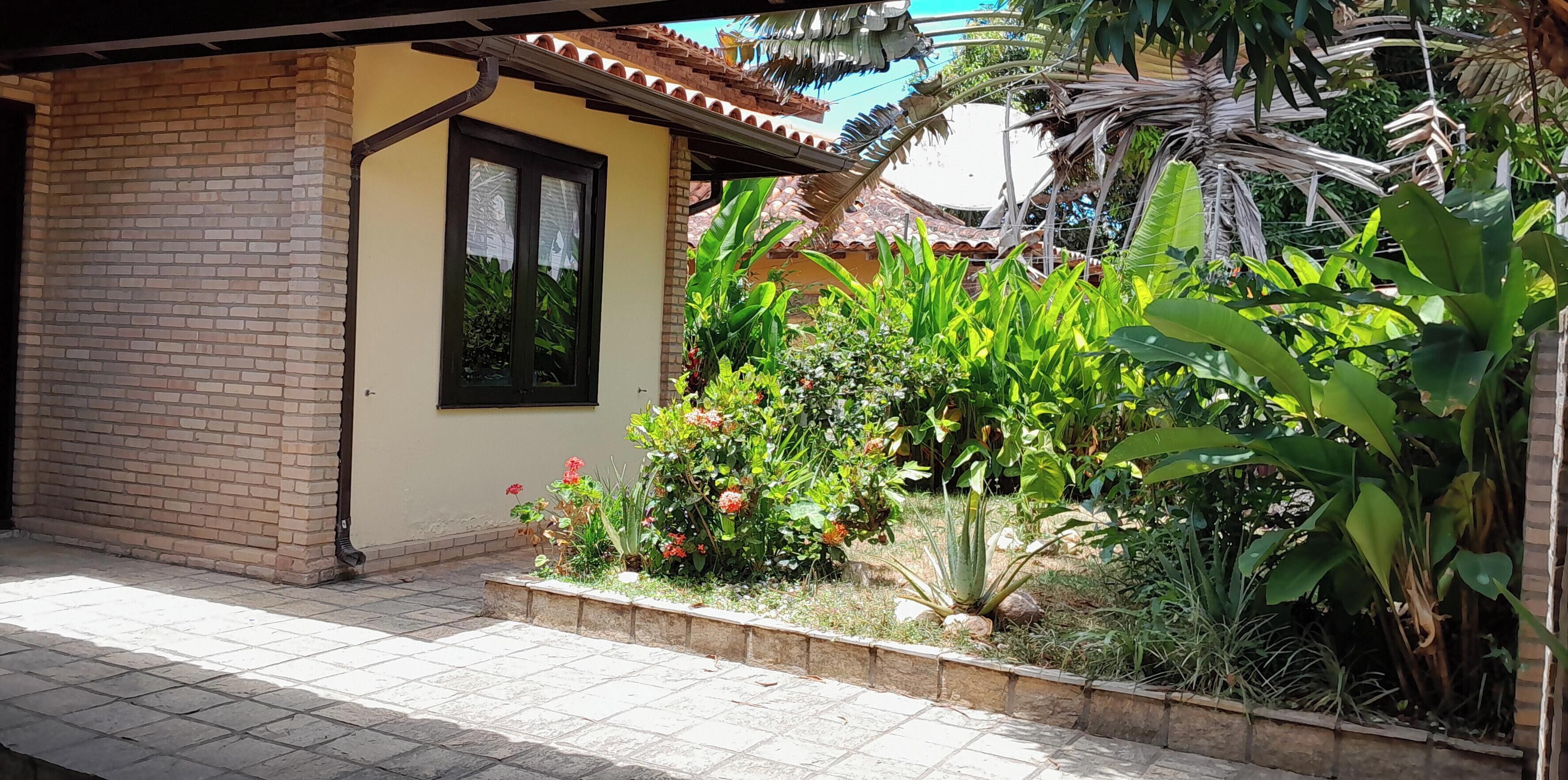 A brick building with a tiled patio and a garden with various plants and flowers.