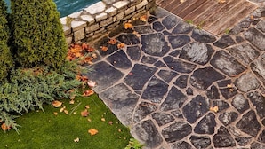 Une terrasse en pierre avec une rambarde en métal donnant sur une étendue d’eau.