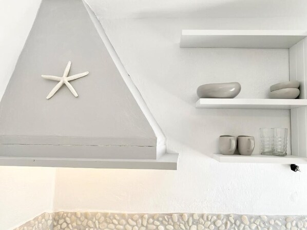A modern interior with a white wall, a starfish decoration, and a shelf with decorative items.