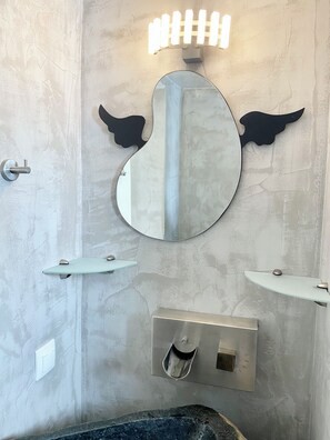 Une salle de bain avec un grand miroir rond, deux lavabos et des toilettes.