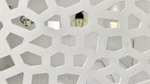 A geometric wall with hexagonal cutouts, some containing objects. - CABARNUS HOUSE in the HEART of Paroikia, Paros! (Paros)