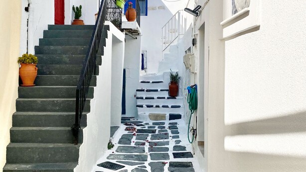 A narrow street with stone steps leading to a building with a red door and potted plants. - CABARNUS HOUSE in the HEART of Paroikia, Paros! (Paros)