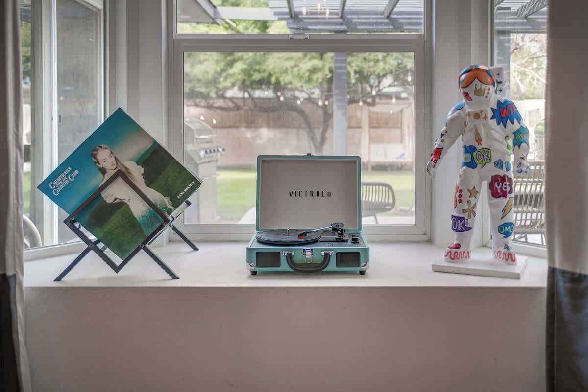 Een raam met een vinylspeler, een lijst met foto en een beeldje op de vensterbank.