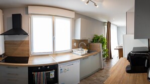 A modern kitchen with a dishwasher, stove, and a large window. - Résidence Hera Paris Orly Aéroport (Villeneuve-le-Roi)