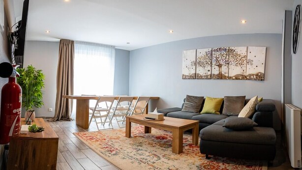 A modern living room with a sofa, coffee table, and a dining area with chairs. - Résidence Hera Paris Orly Aéroport (Villeneuve-le-Roi)