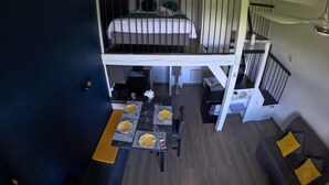 Una stanza su due livelli, con un letto a castello al piano superiore e un'area pranzo al piano inferiore.