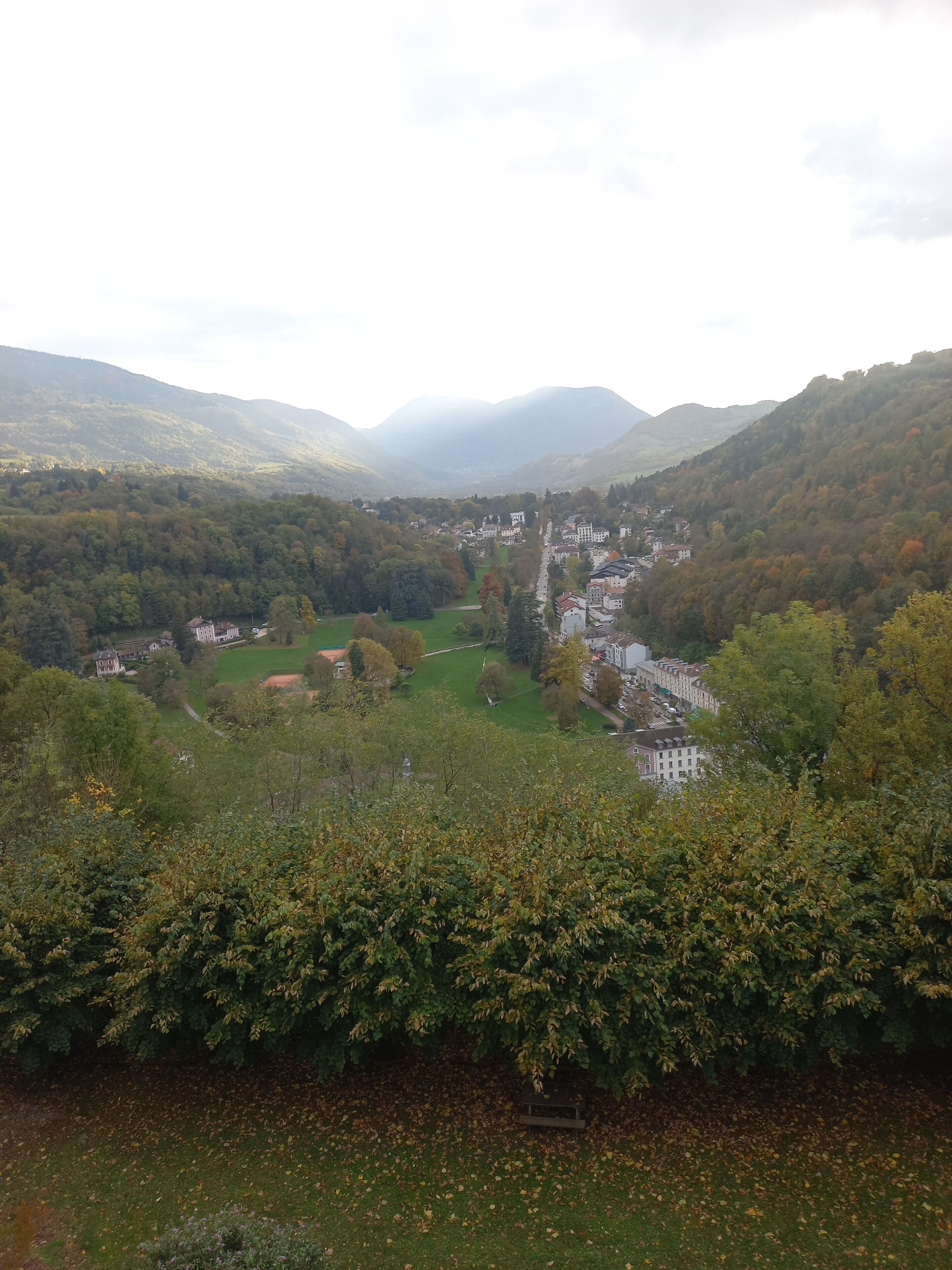 Una valle con un paese incastonato tra le colline, circondato da fitti boschi e vegetazione.
